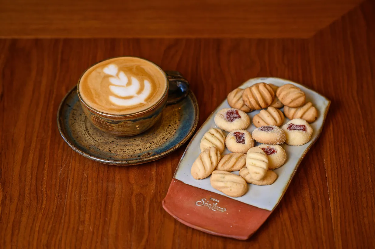 Cappuccino com latte art e biscoitos na bandeja da Casa São Lucas