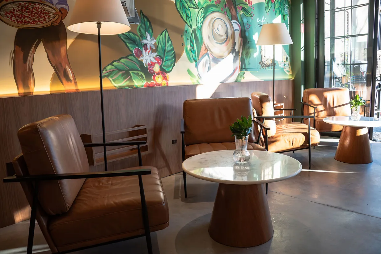 Lounge da Casa São Lucas com poltronas de couro e o mural ao fundo